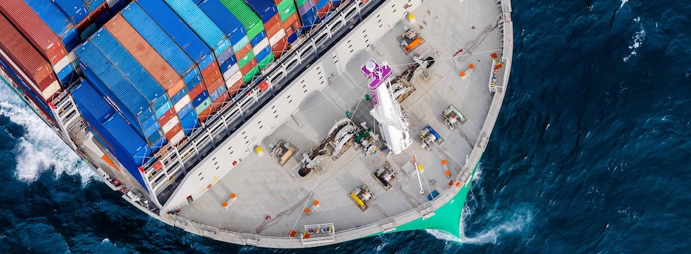 Vue aérienne d'un porte-conteneurs en mer transportant des conteneurs multicolores empilés sur le pont, illustration du transport maritime international et du fret commercial.