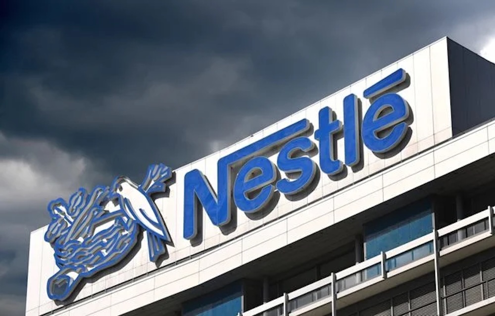 Façade du siège de Nestlé à Vevey, avec le logo bleu de l’entreprise sous un ciel nuageux.