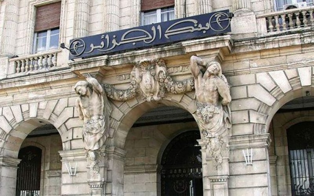 Façade néoclassique de la Banque d'Algérie à Alger, avec colonnes et cariatides sculptées, et inscription en arabe au sommet du bâtiment.