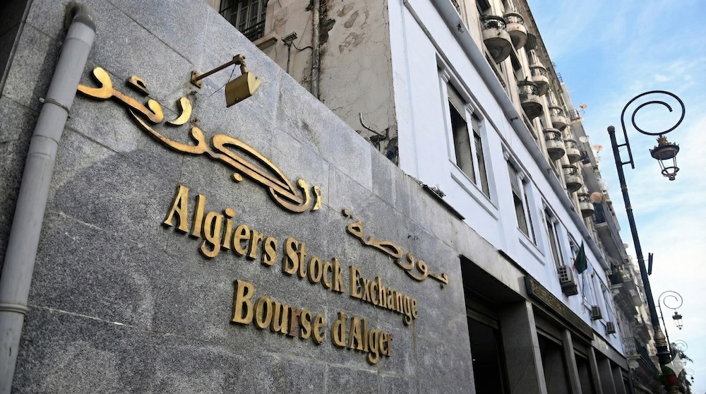 Texte alt : Plaque en lettres dorées de la Bourse d'Alger (Algiers Stock Exchange) en arabe et en français, fixée sur la façade en pierre du bâtiment.