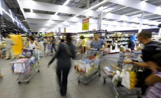 Client poussant un chariot dans les rayons d'un supermarché