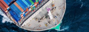 Vue aérienne d'un porte-conteneurs en mer transportant des conteneurs multicolores empilés sur le pont, illustration du transport maritime international et du fret commercial.