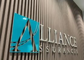 Logo Alliance Assurances en lettres relief sur fond de boiseries, siège social de la compagnie.