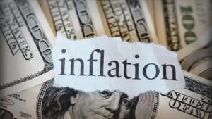 Mot inflation écrit sur un morceau de papier posé sur des billets de cent dollars américains