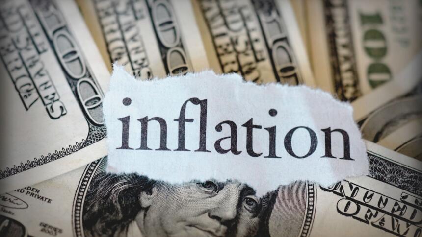 Mot inflation écrit sur un morceau de papier posé sur des billets de cent dollars américains
