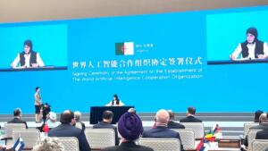 Meriem Benmouloud signant l'accord fondateur de l'Organisation mondiale de coopération en intelligence artificielle à Shanghai, drapeau algérien projeté à l'écran