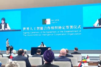 Meriem Benmouloud signant l'accord fondateur de l'Organisation mondiale de coopération en intelligence artificielle à Shanghai, drapeau algérien projeté à l'écran