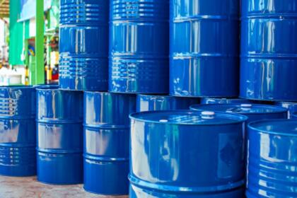 Fûts métalliques bleus empilés sur une aire de stockage industrielle
