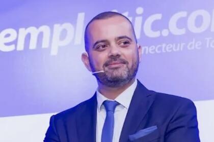 Tarik Metnani, CEO d'Emploitic, bras croisés, micro-cravate, devant un fond floqué du logo Emploitic.com.