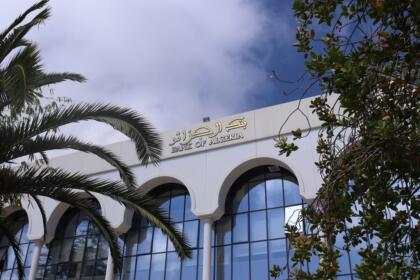 Façade du siège de la Banque d'Algérie à Alger, avec l'enseigne "Bank of Algeria" en arabe et en anglais, sous un ciel dégagé.
