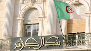 Façade du siège de la Banque d'Algérie à Alger avec le drapeau national algérien flottant devant l'entrée.