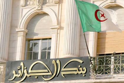 Façade du siège de la Banque d'Algérie à Alger avec le drapeau national algérien flottant devant l'entrée.