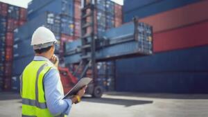 Agent portuaire vérifiant un dossier d'exportation devant des conteneurs
