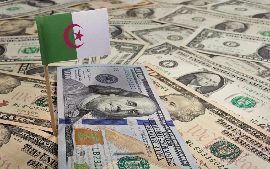 Drapeau algérien planté dans des billets de dollars américains, illustrant l'exposition de l'Algérie à la devise américaine.