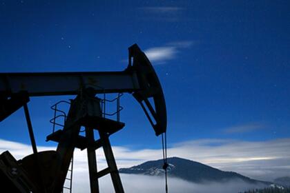 Pompe à pétrole (derrick) silhouettée la nuit sous un ciel étoilé