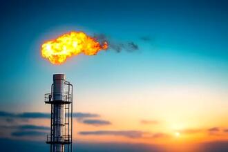 torchère de gaz en combustion sur un site pétrolier au coucher du soleil