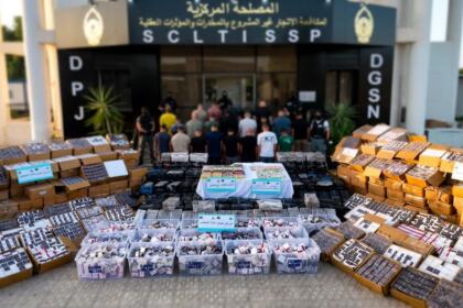 Cartons et bacs de comprimés et de plaquettes de drogue disposés au sol devant le siège du Service central de lutte contre le trafic illicite de stupéfiants, à Alger.