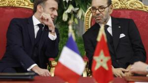 Emmanuel Macron et le roi Mohammed VI assis côte à côte, drapeaux français et marocain au premier plan.