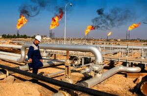 Ouvrier casqué sur un site de production de gaz, pipelines et torchères en arrière-plan