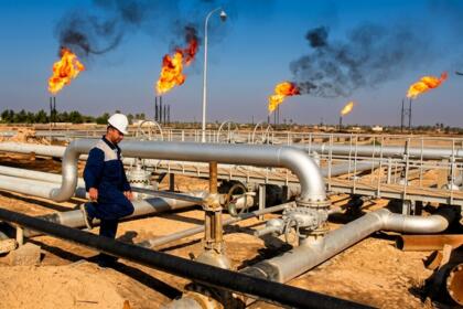 Ouvrier casqué sur un site de production de gaz, pipelines et torchères en arrière-plan
