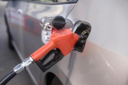 Pistolet de pompe à essence inséré dans le réservoir d'une voiture, illustrant la hausse des prix du carburant en France