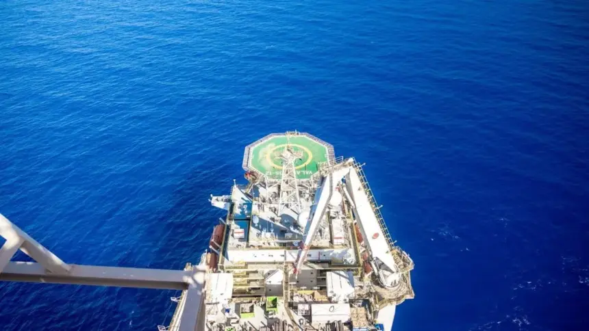 Vue aérienne d'un navire de forage en haute mer, avec un hélipad vert portant l'inscription « Valaris DS-12 » et des grues sur le pont, entouré d'une mer bleu foncé.