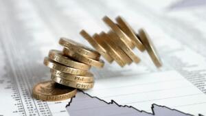 Pièces de monnaie empilées sur des pages de cotations boursières, illustrant un article sur le lancement d'un master en finance islamique par la COSOB et la collecte du sukuk souverain algérien.