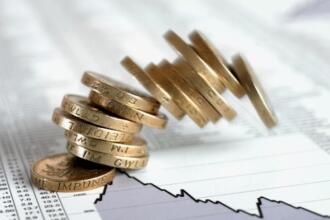 Pièces de monnaie empilées sur des pages de cotations boursières, illustrant un article sur le lancement d'un master en finance islamique par la COSOB et la collecte du sukuk souverain algérien.