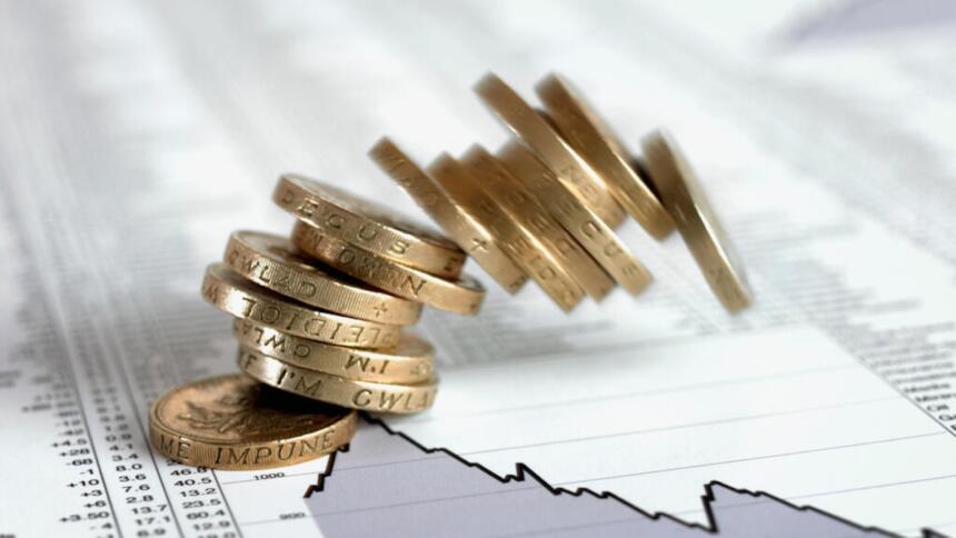 Pièces de monnaie empilées sur des pages de cotations boursières, illustrant un article sur le lancement d'un master en finance islamique par la COSOB et la collecte du sukuk souverain algérien.