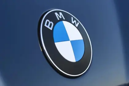 Logo BMW en gros plan sur la carrosserie bleu foncé d'une voiture, illustrant le retour de BMW en Algérie