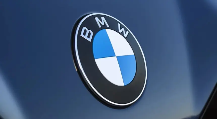Logo BMW en gros plan sur la carrosserie bleu foncé d'une voiture, illustrant le retour de BMW en Algérie