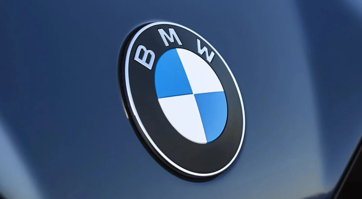 Logo BMW en gros plan sur la carrosserie bleu foncé d'une voiture, illustrant le retour de BMW en Algérie