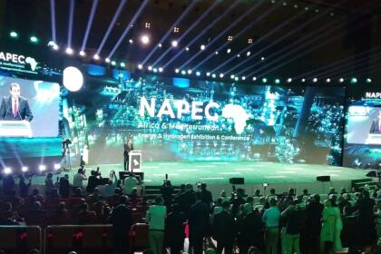 Mohamed Arkab au pupitre sur la scène du NAPEC 2025, devant un écran géant portant le logo du salon, face à une salle comble au Centre des conventions d’Oran.