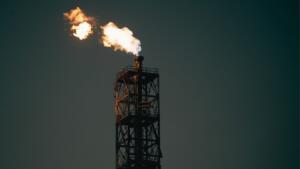 Torchère d'une installation pétrolière brûlant du gaz dans un ciel sombre