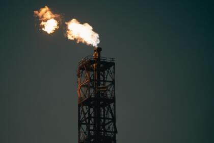 Torchère d'une installation pétrolière brûlant du gaz dans un ciel sombre