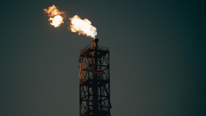 Torchère d'une installation pétrolière brûlant du gaz dans un ciel sombre