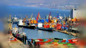 Porte-conteneurs et grues à quai dans un port algérien, avec des piles de conteneurs au premier plan.