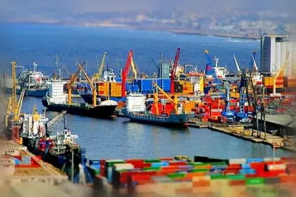 Porte-conteneurs et grues à quai dans un port algérien, avec des piles de conteneurs au premier plan.