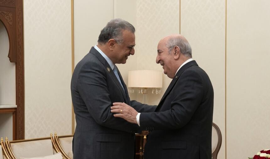 عبد المجيد تبون ومسعد بولس يتصافحان ويتبادلان الابتسام في صالون رئاسي بألوان كريمية وذهبية، بالجزائر العاصمة.