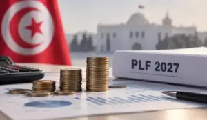 Pièces de monnaie empilées devant un classeur « PLF 2027 », avec un drapeau tunisien et un bâtiment officiel en arrière-plan