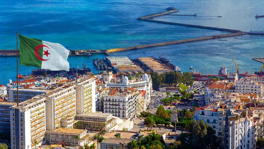 Vue aérienne du port d’Alger, avec ses jetées, ses navires à quai et les immeubles blancs du front de mer.