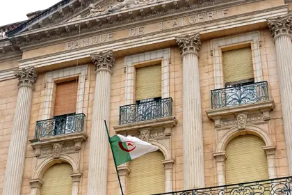 Façade néoclassique de la Banque d’Algérie, avec l’inscription « Banque de l’Algérie » et un drapeau algérien devant les colonnes.