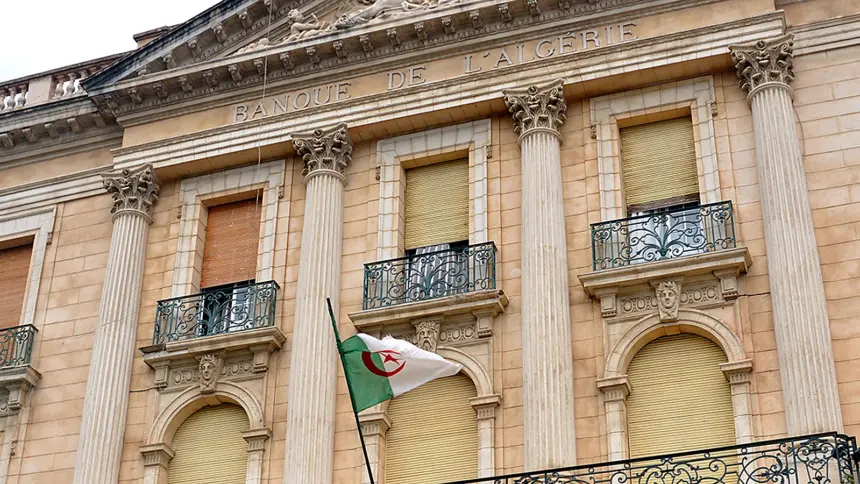 Façade néoclassique de la Banque d’Algérie, avec l’inscription « Banque de l’Algérie » et un drapeau algérien devant les colonnes.
