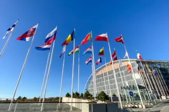 Drapeaux européens devant un bâtiment vitré, en illustration d’un article sur la BEI et la transition énergétique en Algérie