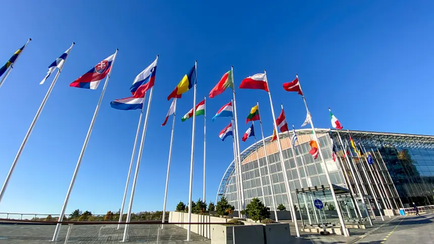 Drapeaux européens devant un bâtiment vitré, en illustration d’un article sur la BEI et la transition énergétique en Algérie