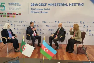 Quatre personnes en entretien devant le panneau de la 28e réunion ministérielle du GECF à Moscou, avec les drapeaux de l’Algérie et de l’Azerbaïdjan sur la table.