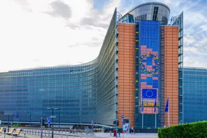 Façade vitrée incurvée du Berlaymont, siège de la Commission européenne à Bruxelles, avec des drapeaux européens devant l'entrée.