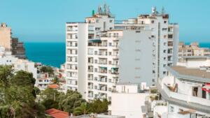 Immeubles d’habitation blancs dans une ville côtière, avec la mer à l’horizon sous un ciel dégagé