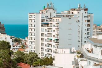 Immeubles d’habitation blancs dans une ville côtière, avec la mer à l’horizon sous un ciel dégagé