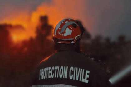 Un agent de la Protection civile, de dos, face aux flammes lors des incendies de Jijel.